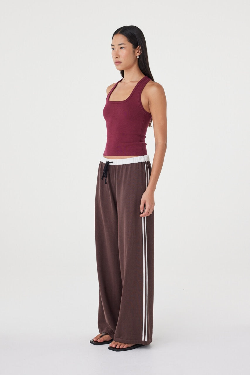 Side profile of the Tully Pant in espresso and cream paired with a fitted merlot tank, showing the fluid silhouette, contrast waistband and soft drape through the leg