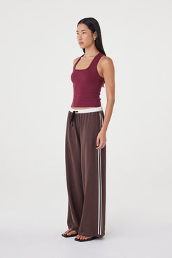 Side profile of the Tully Pant in espresso and cream paired with a fitted merlot tank, showing the fluid silhouette, contrast waistband and soft drape through the leg