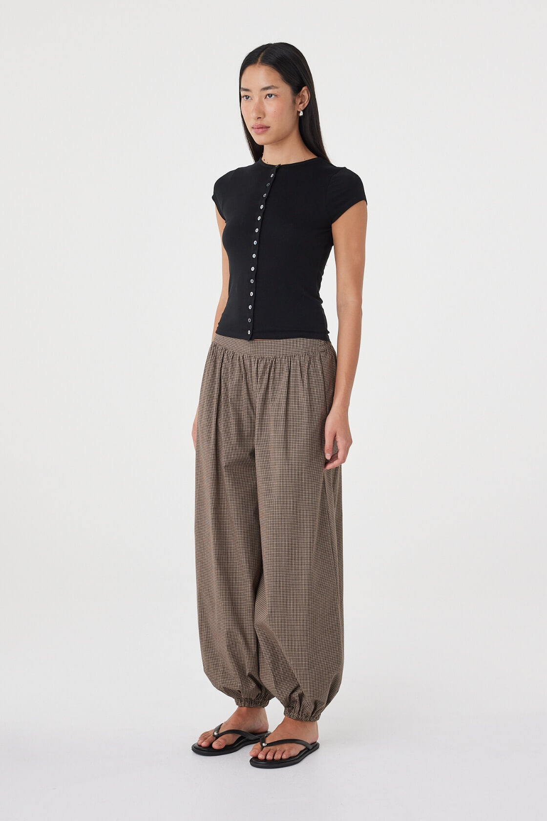 Side view of the Elina Balloon Pant in Chocolate Check highlighting the soft balloon silhouette, gathered hem and relaxed drape, paired with the Robbie Top in Black.