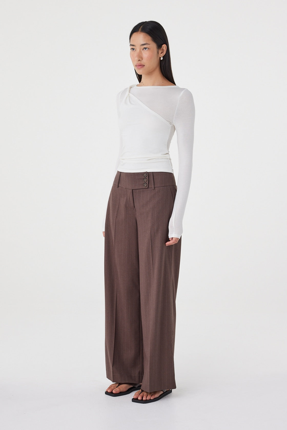 Side view of the Manon Pant in Espresso Pinstripe highlighting the relaxed wide-leg silhouette and fluid drape through the leg.