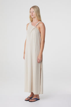 Clara Maxi Dress in Taupe, three quarter view highlighting the asymmetrical neckline and long, loose silhouette.