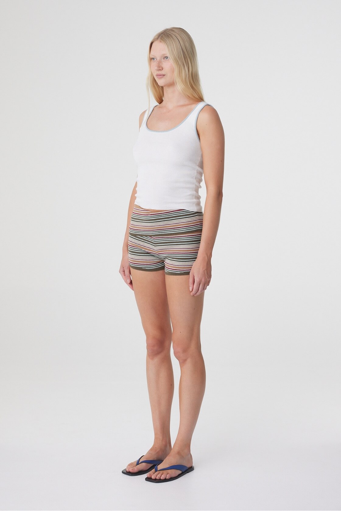 Model wearing the Tove Short in Olive Stripe with a white tank, side view showing the mini length and close fit.