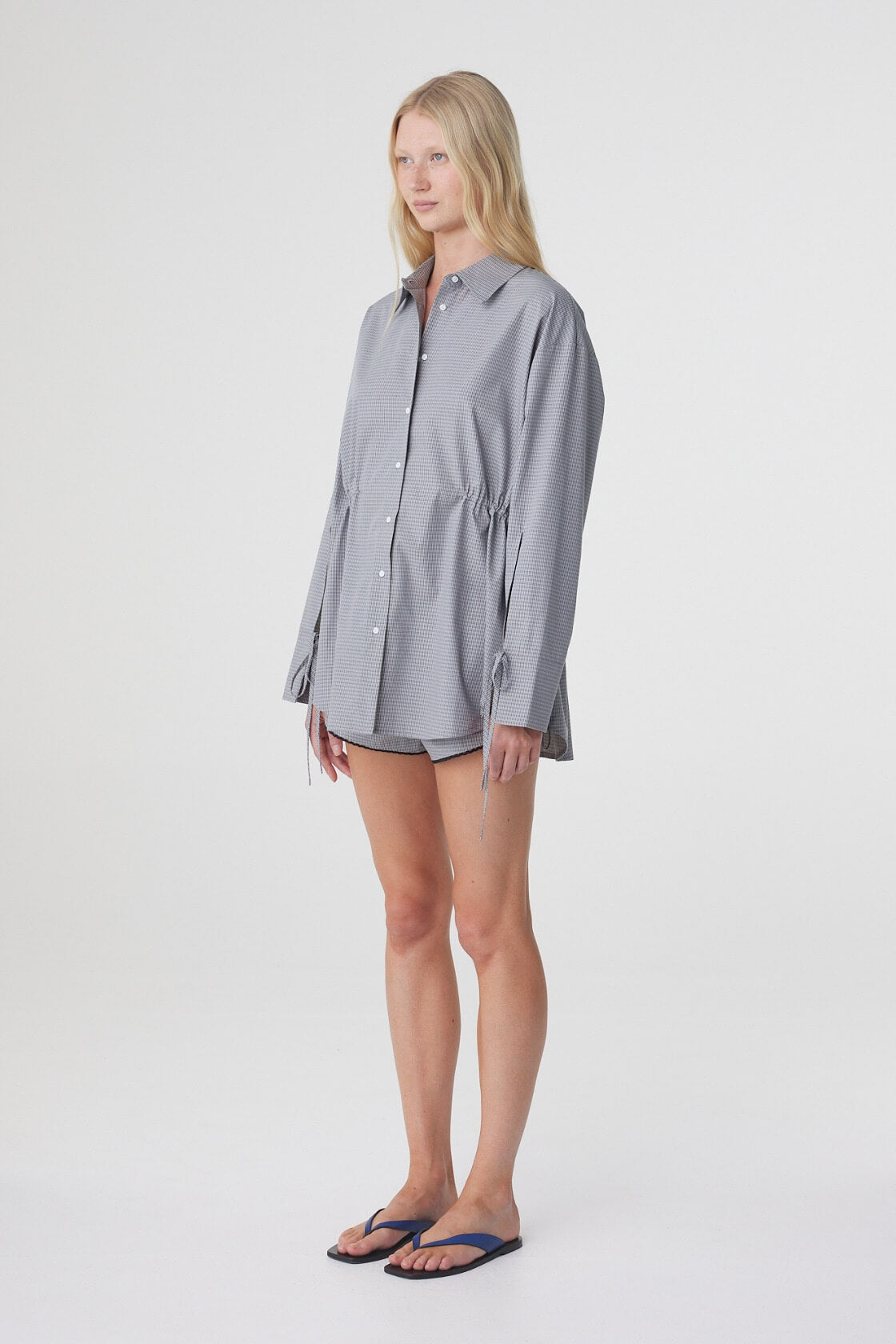 Three quarter view of the Sia Shirt in Muted Blue Check, showing the relaxed shape and tie detailing at the cuffs.