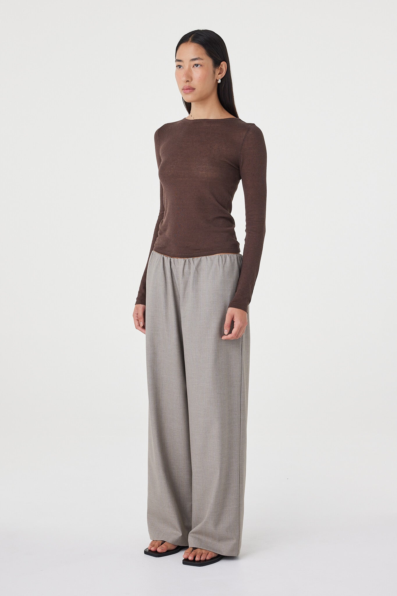Side profile view of the Aston LS Top in espresso paired with taupe wide-leg pants and black sandals, highlighting the close fit through the body and lightweight drape