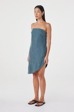 Angled front view of the Rhea Dress in Teal worn on its own, showcasing the strapless shape and asymmetric midi hem.