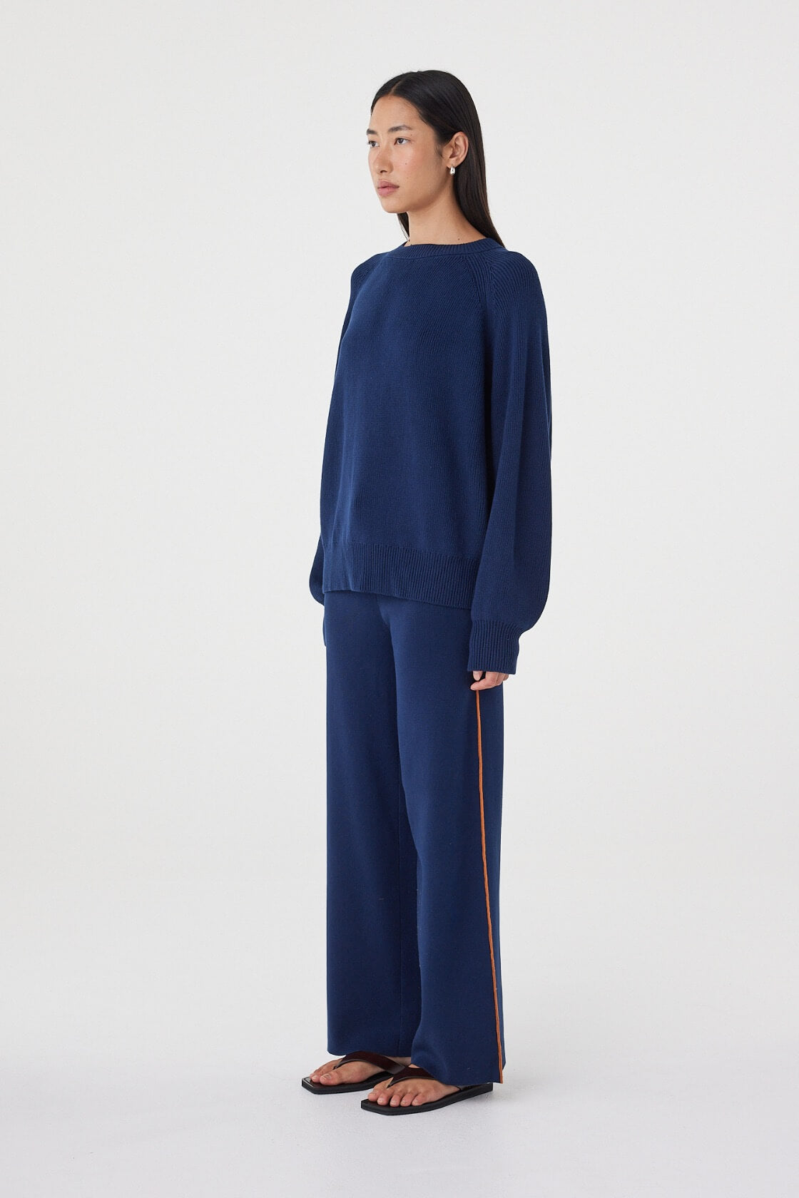 Side view of the Aubrey Sweater in Navy showing the easy drape, relaxed sleeves and subtle volume through the body.