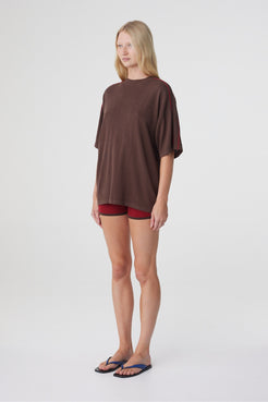 Tove Short in Chilli, three quarter view styled with an oversized espresso tee, showing the short length and close fit.