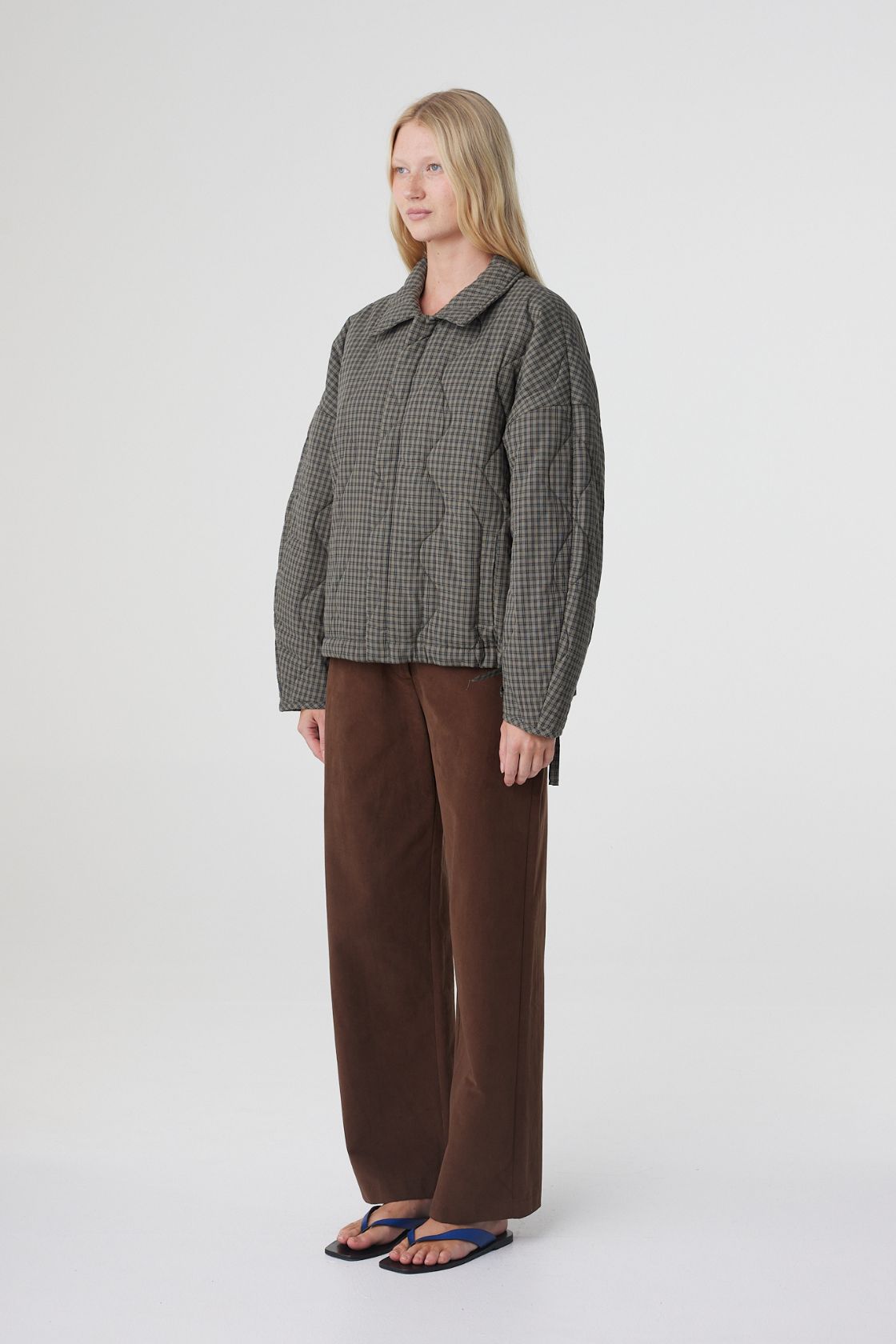 Side profile of the Matteo quilted jacket in olive and teal check, highlighting the cocoon shape, rounded sleeves and oversized fit