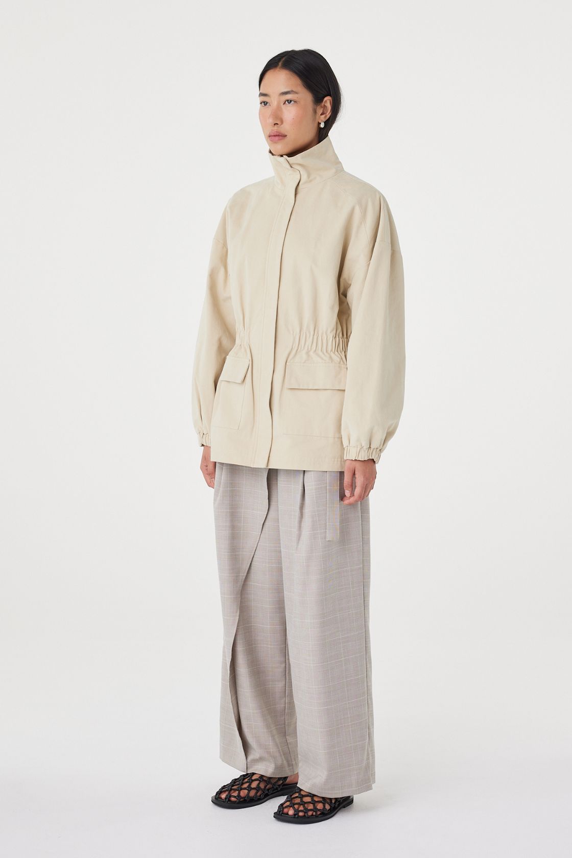 Side view of the Amari Jacket in Beige showing the relaxed silhouette, elasticated cuffs and lightweight structure.