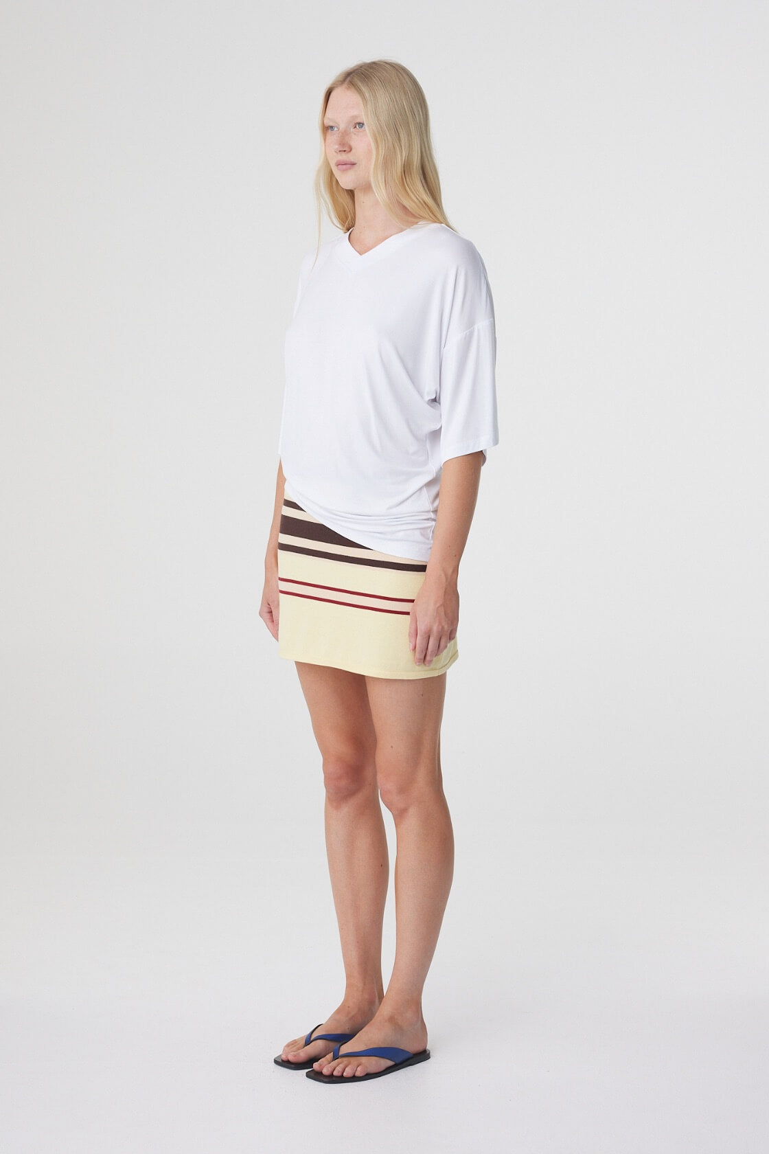Mara Mini Skirt in Butter Espresso Stripe, three quarter view styled with a relaxed white tee and flat sandals.