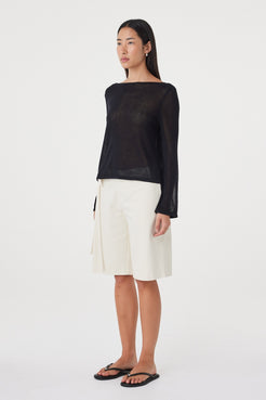 Side view of the Nia LS Top in Black highlighting the loose silhouette, long sleeves and semi-sheer finish.