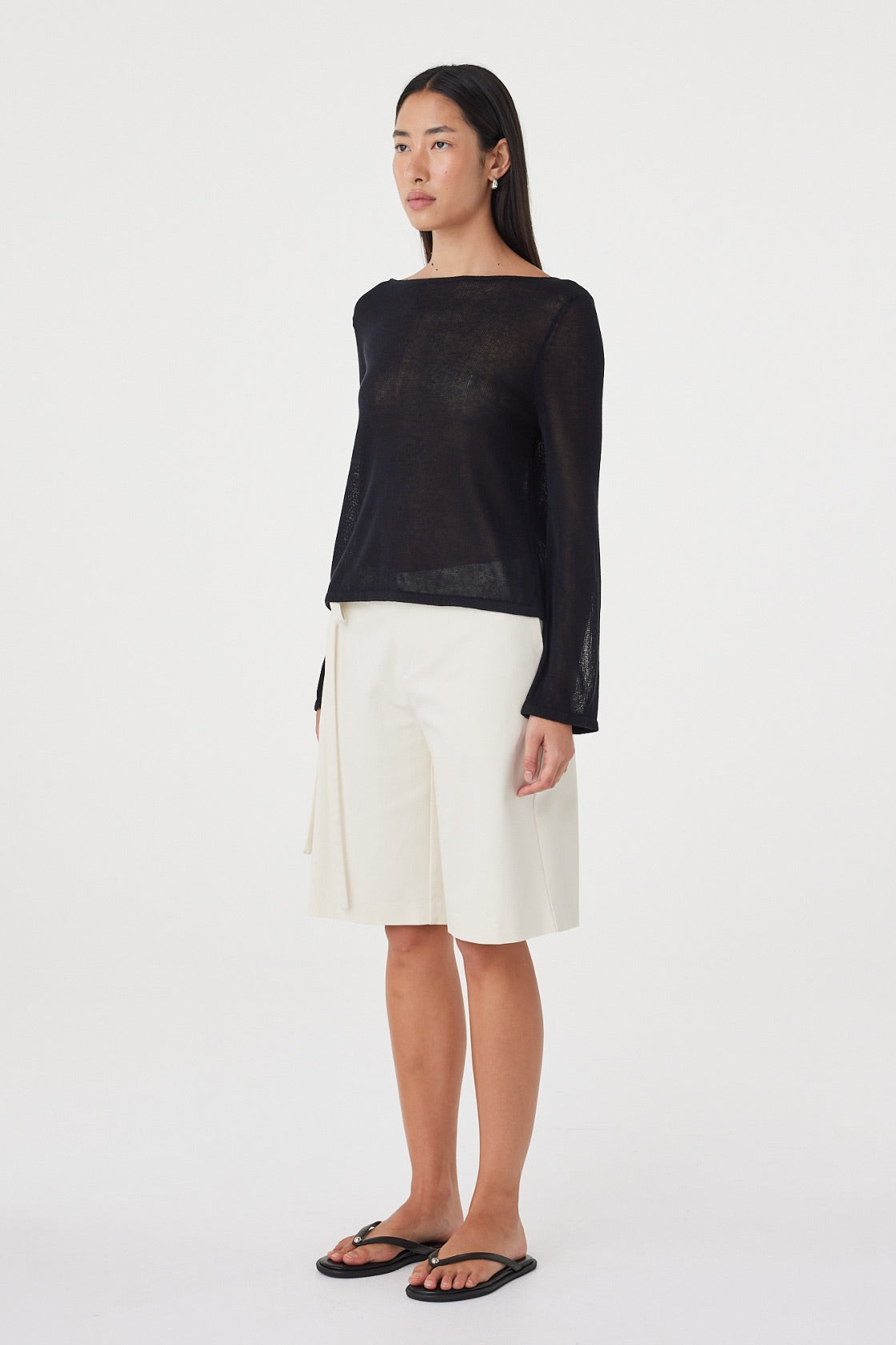 Side view of the Nia LS Top in Black highlighting the loose silhouette, long sleeves and semi-sheer finish.