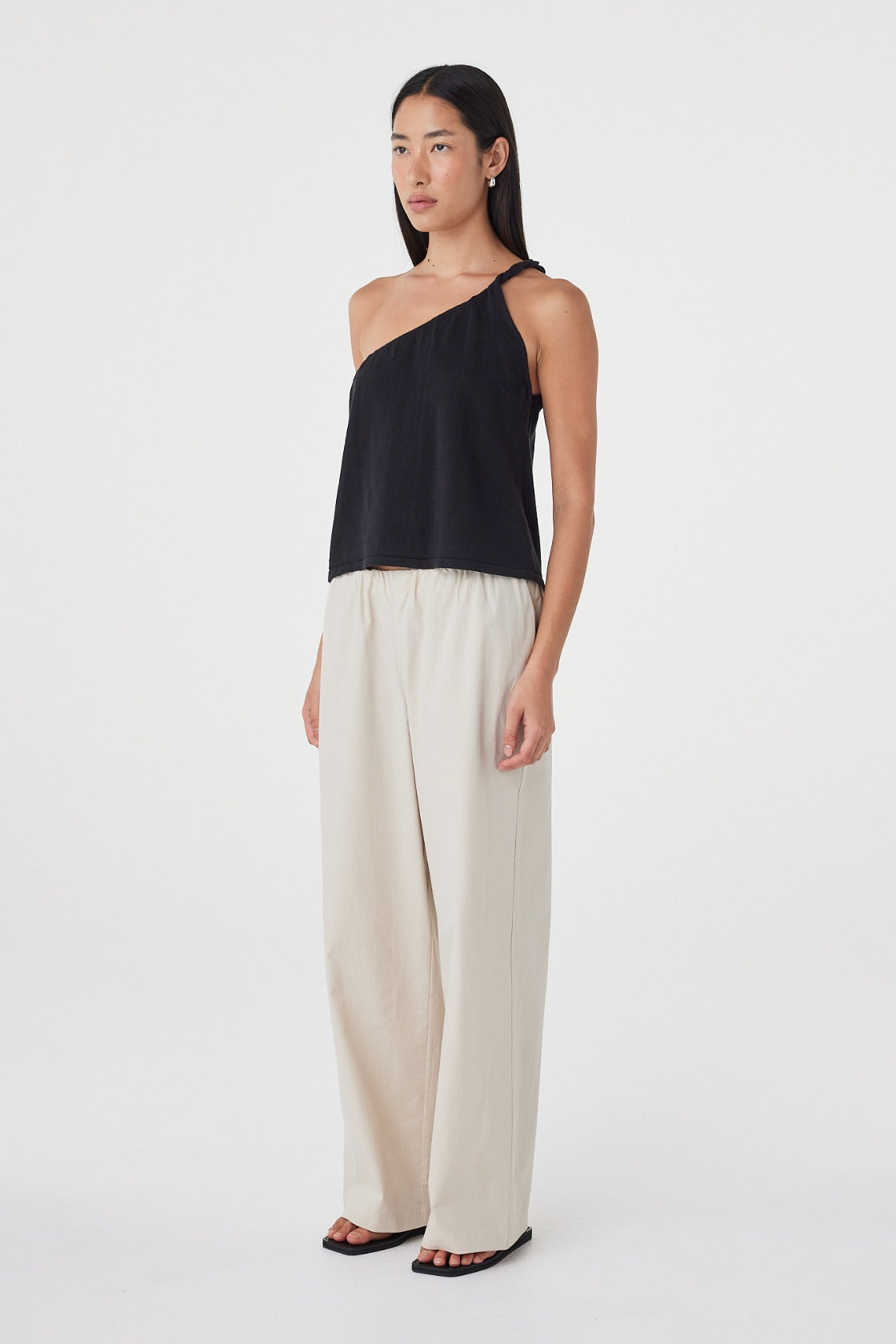 Side view of the Harri Asym Top in Black showing the one-shoulder construction and easy, off-body drape.