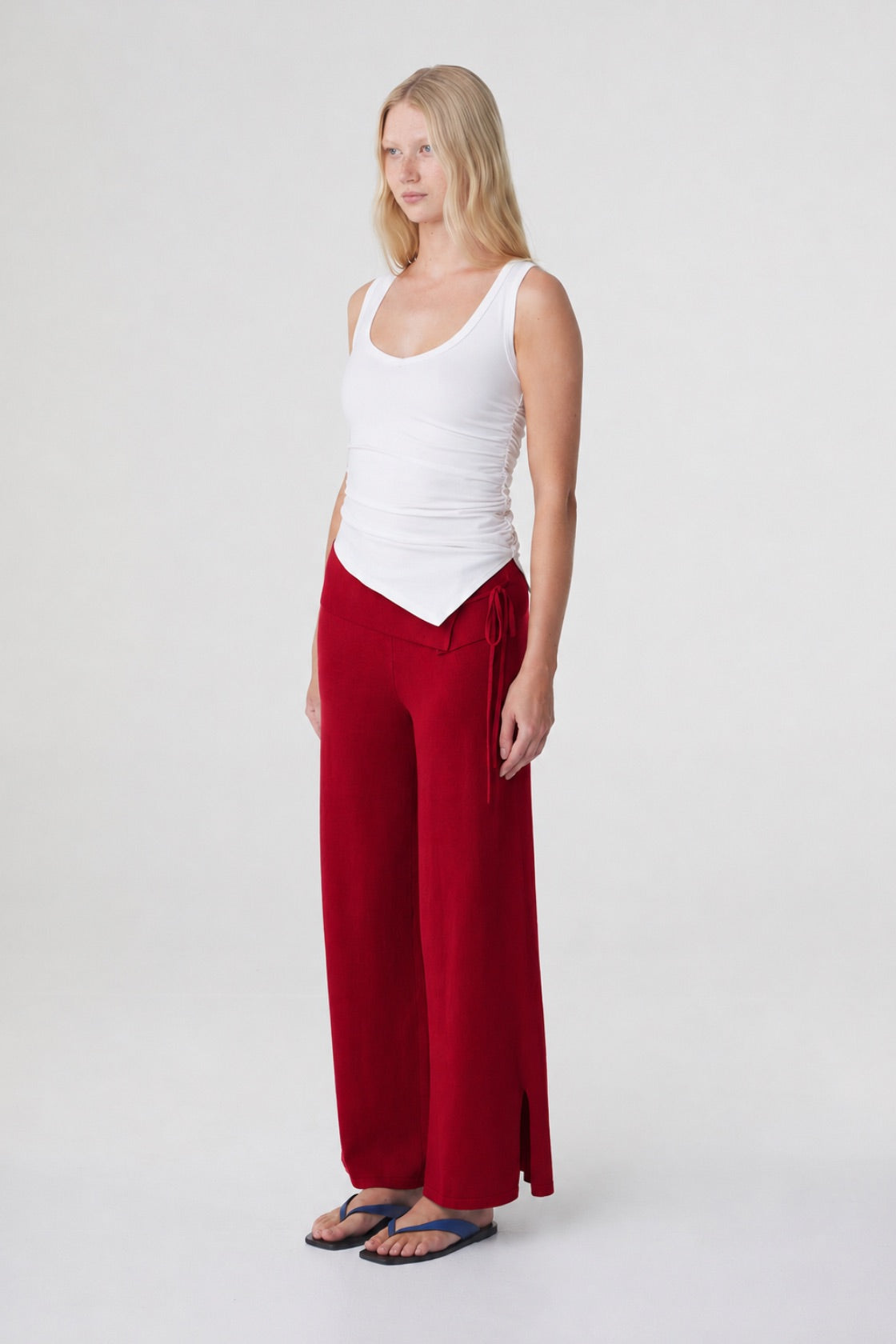Nora Pant in Chilli, three quarter view styled with a white tank, showing the full length relaxed silhouette and side hem split.