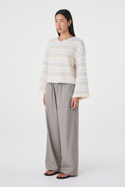 Side profile view of the Lucca Sweater in taupe and blue stripe highlighting the dropped shoulder shape, wide sleeves and soft drape through the body paired with taupe relaxed pants