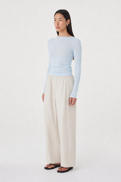 Aston LS Top in Pale Blue styled with the Annika Pants in Taupe, three-quarter side view highlighting the boat neckline, long sleeves and fitted silhouette.