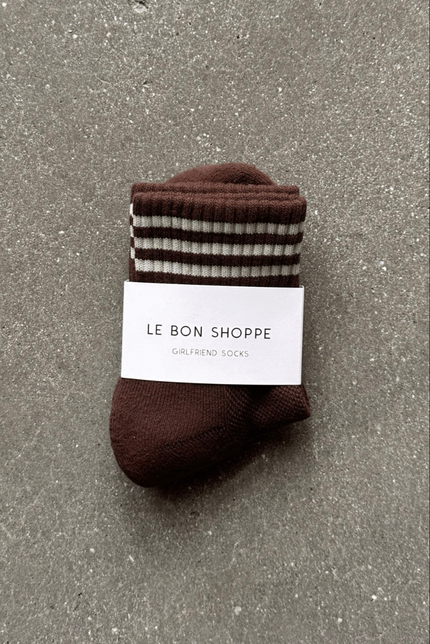 Brown sock with striped pattern and 'Le Bon Shoppe' label on a gray surface
