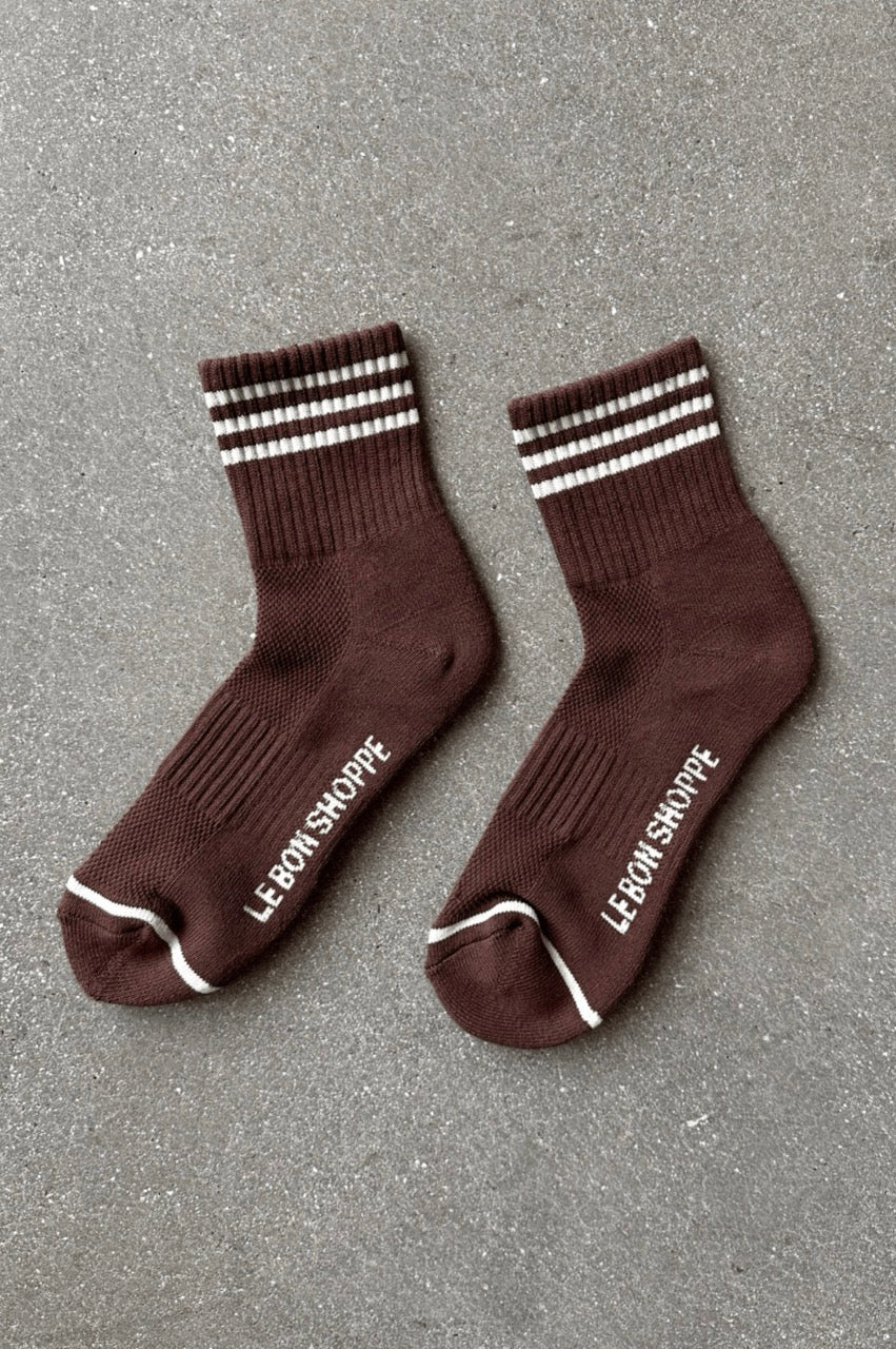 Pair of brown socks with white stripes and text on a gray surface