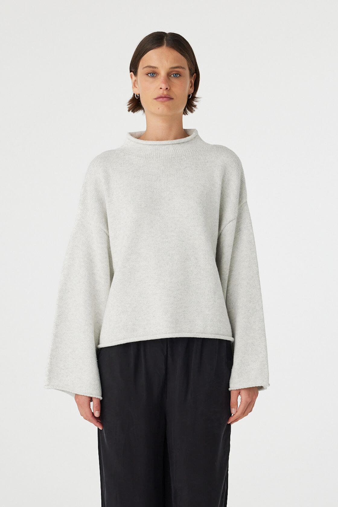 Maeve sweater in snow marle worn front on, featuring a relaxed fit, funnel neckline and cropped length, styled with black wide leg pants