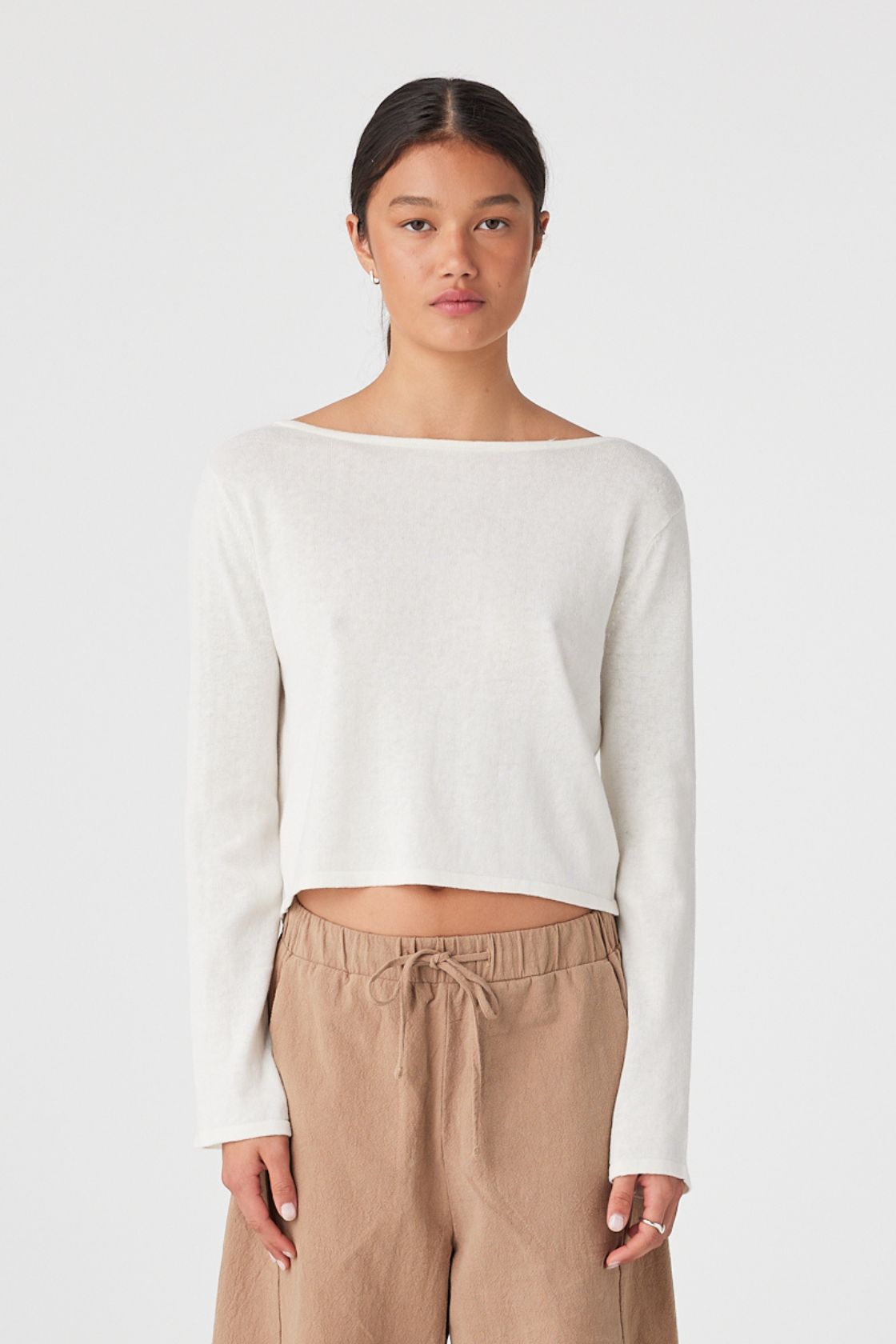 Model in cream long-sleeve knit top with boat neckline and relaxed cropped fit