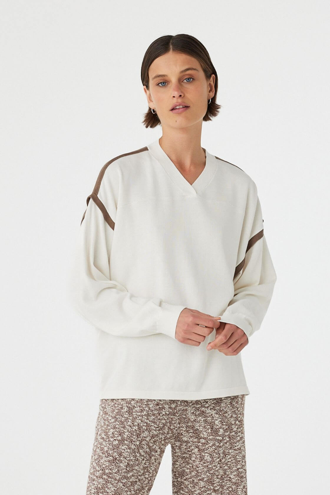 Eden long sleeve tee in cream and espresso worn at an angle, showcasing the contrast stripe detail along the shoulder and armhole, paired with relaxed marled pants