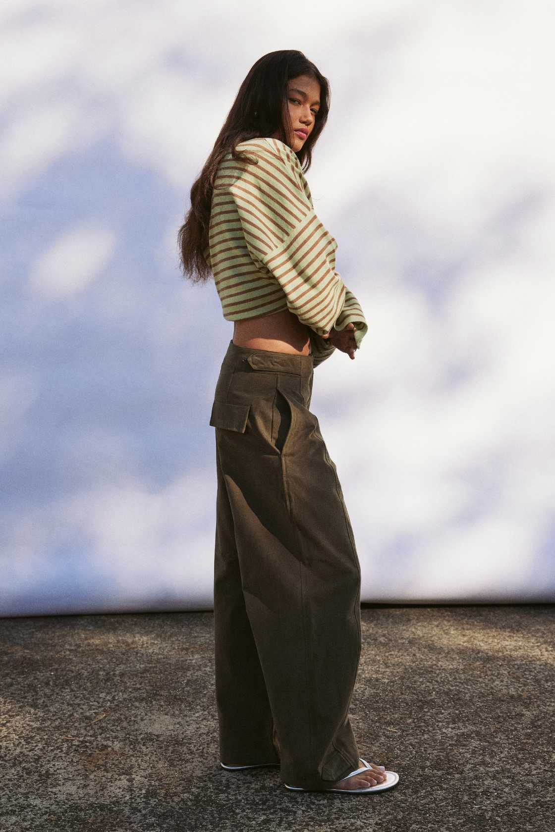 Model wearing khaki velvet-finish cotton barrel-leg pants with front fly zip, roomy leg shape for warm weather