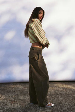 Model wearing khaki velvet-finish cotton barrel-leg pants with front fly zip, roomy leg shape for warm weather