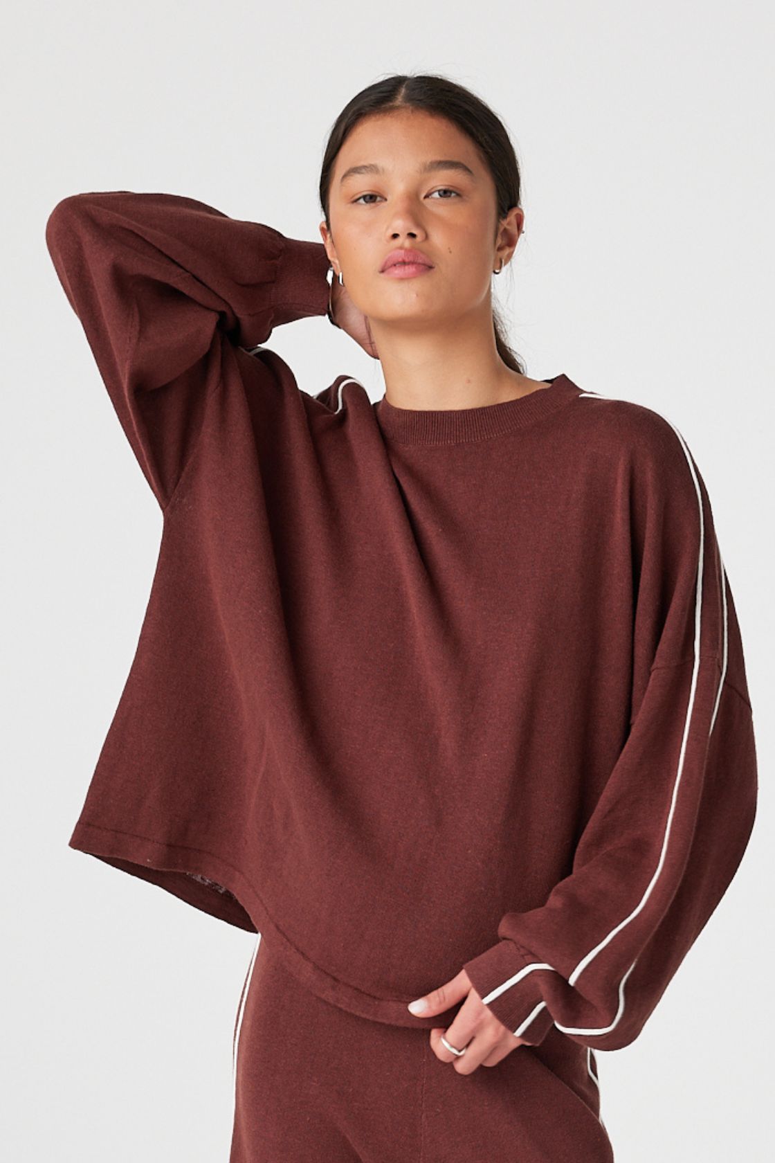 Model wearing Raisin oversized long sleeve knit tee with cream contrast stripe, drop shoulder fit for cool evenings and travel