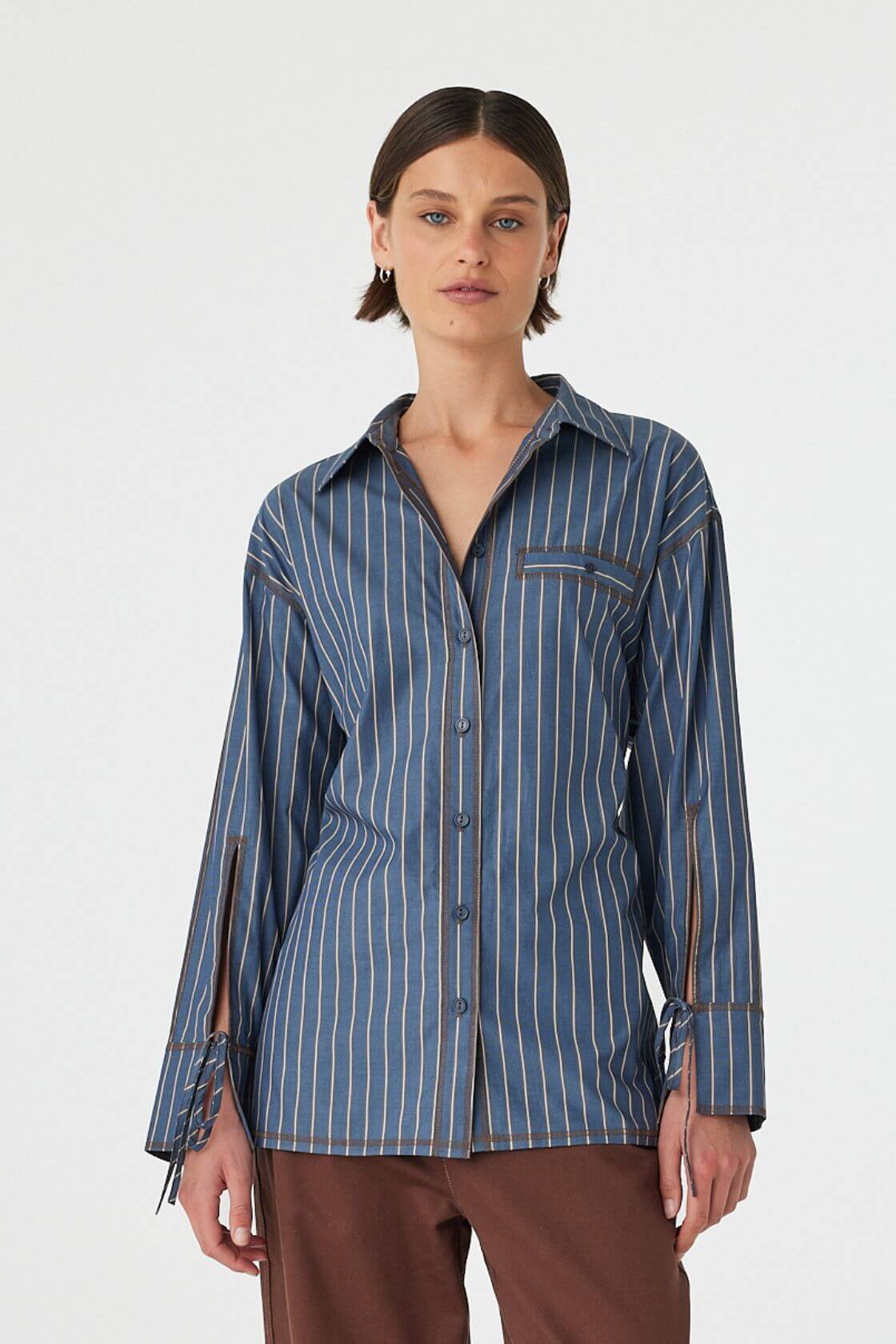 Model wearing Blair Shirt in muted blue stripe, relaxed 100% cotton button-up with long sleeves, front view.