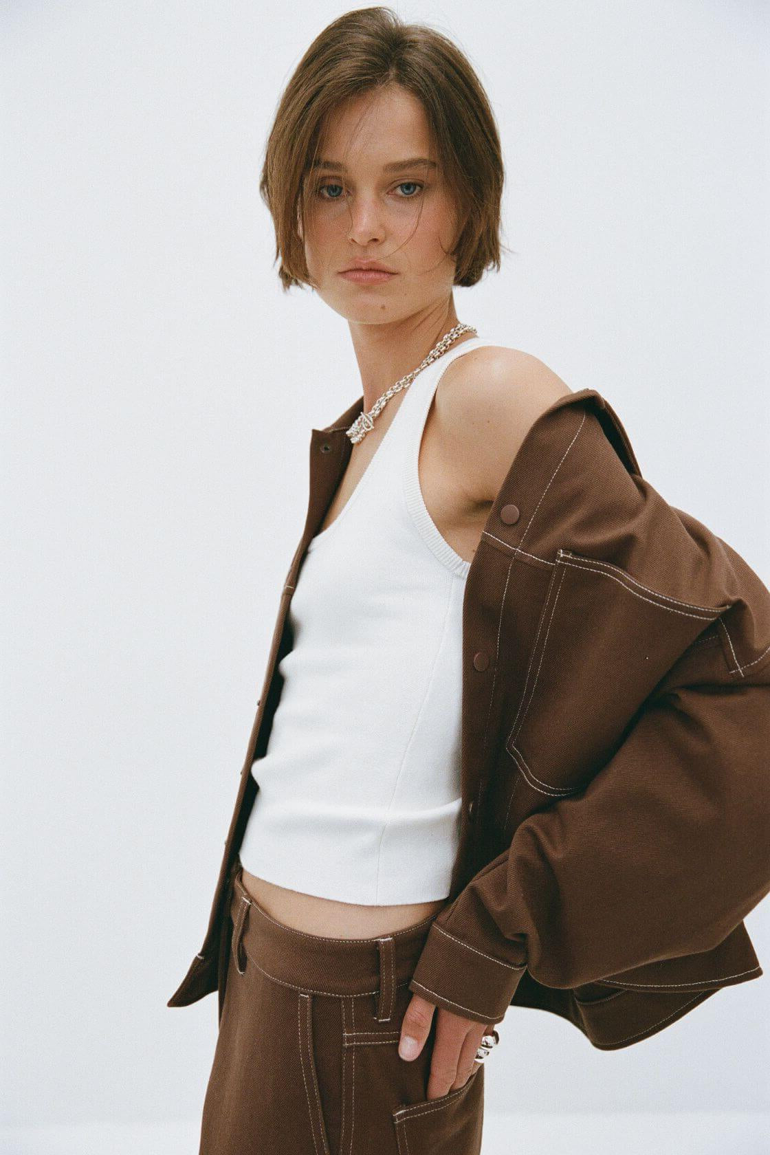 Angled view of brown jacket styled open over white top