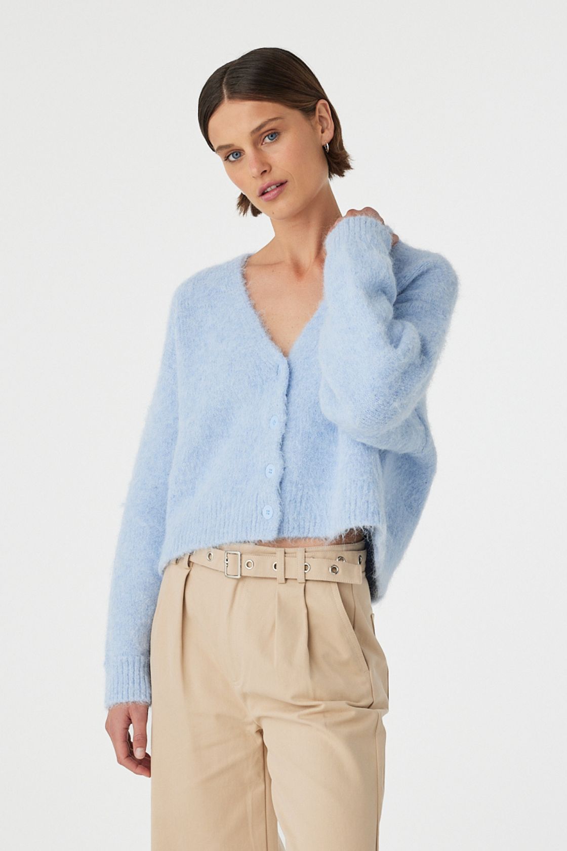 Liora fluffy cardigan in sky worn front on, highlighting the cropped length, ribbed cuffs and hem, and relaxed fit, styled with beige trousers.