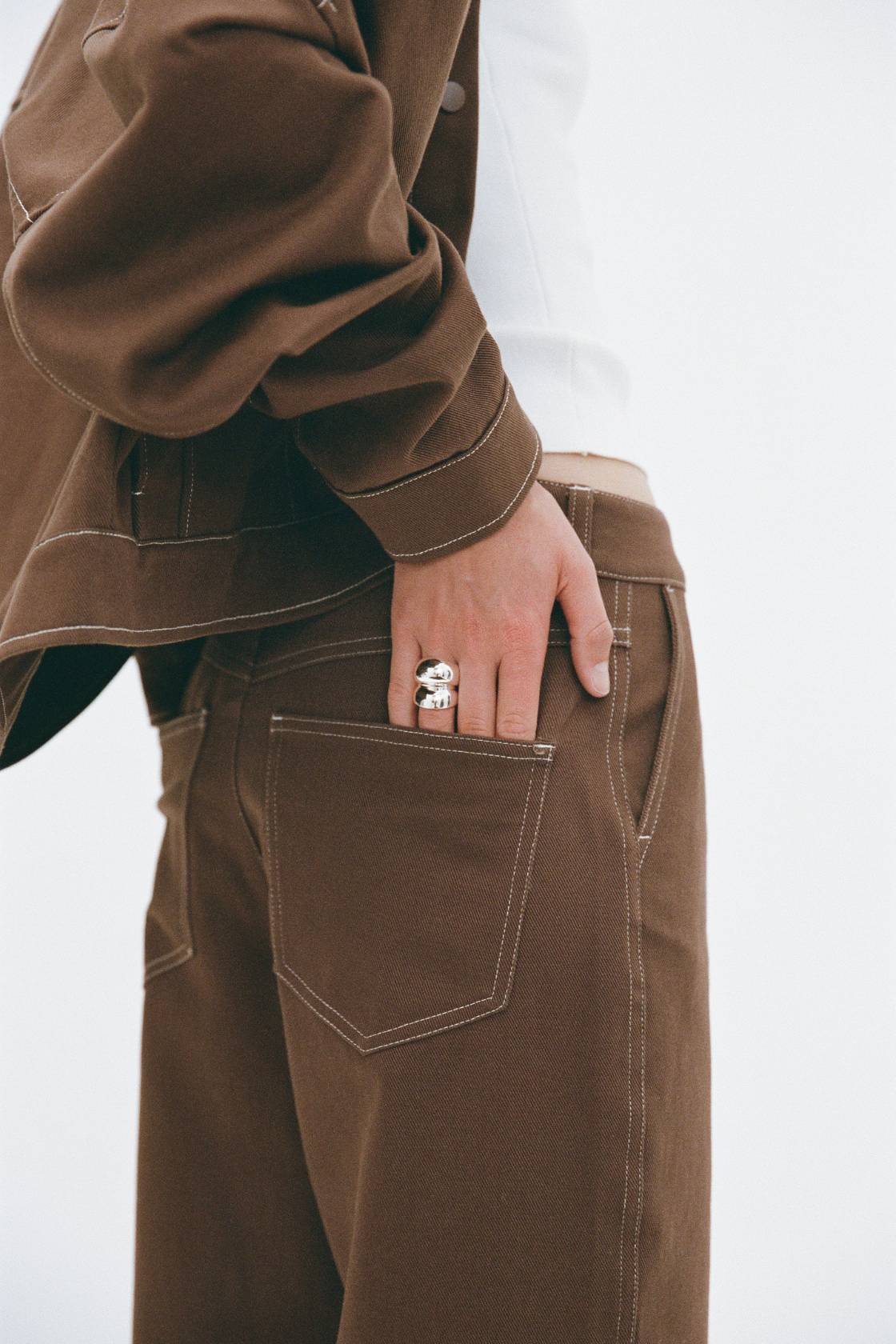 Close pocket detail of Tilda Pant espresso, slash pocket opening and contrast stitching on cotton fabric.
