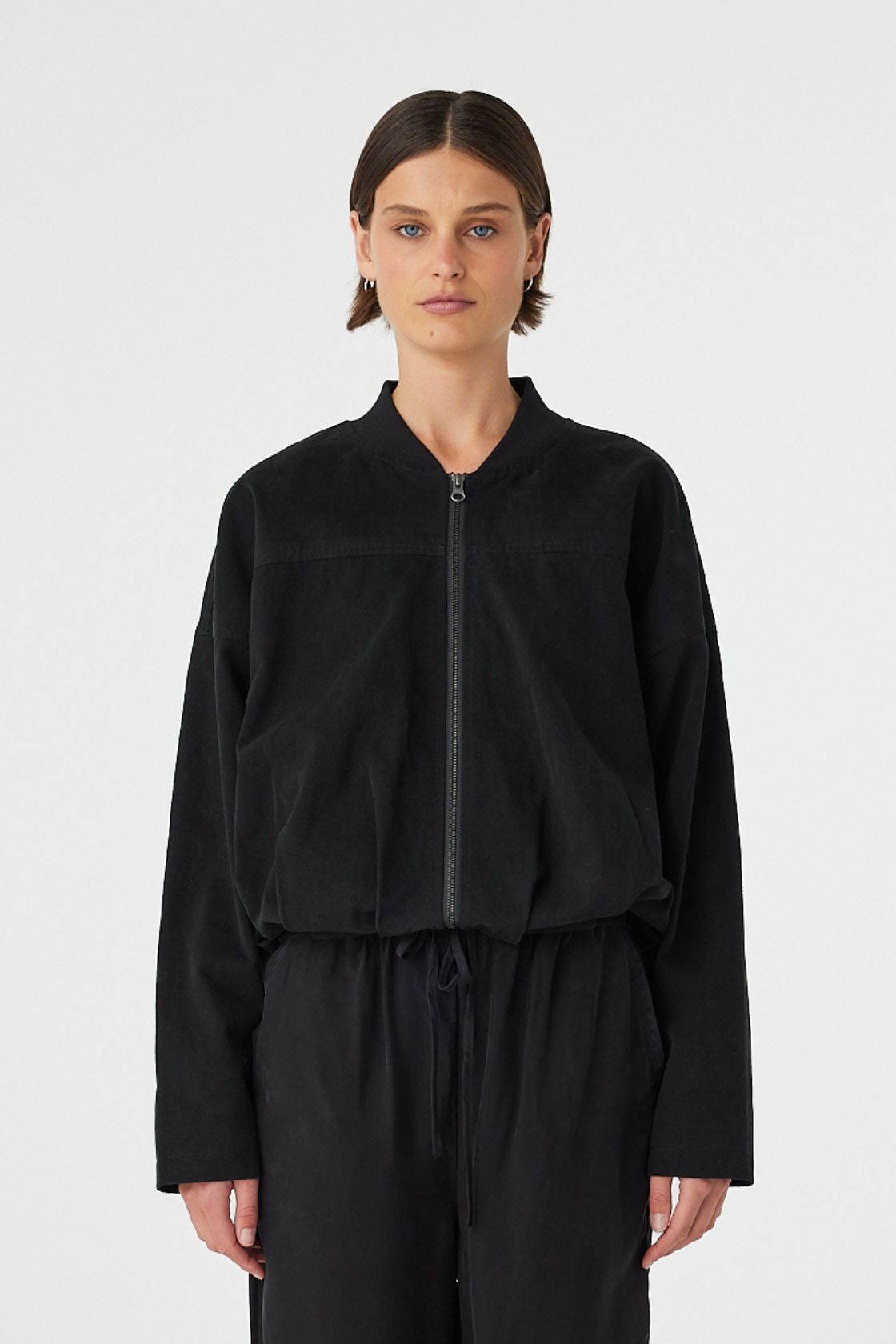 Front view of black bomber jacket with exposed zipper and ribbed collar