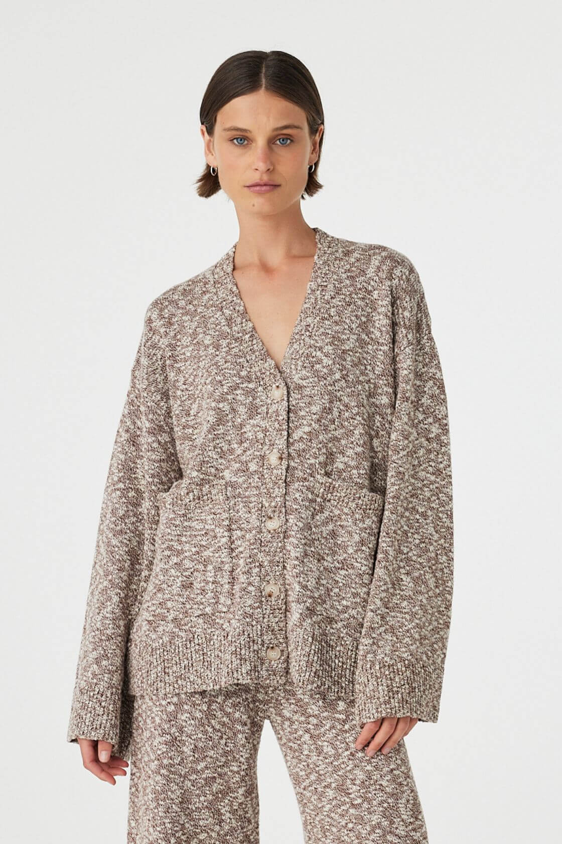 Emmet cardigan in chocolate and cream worn front on, showcasing the longline relaxed fit, textured slub knit and centre front button closure, styled with matching knit pants