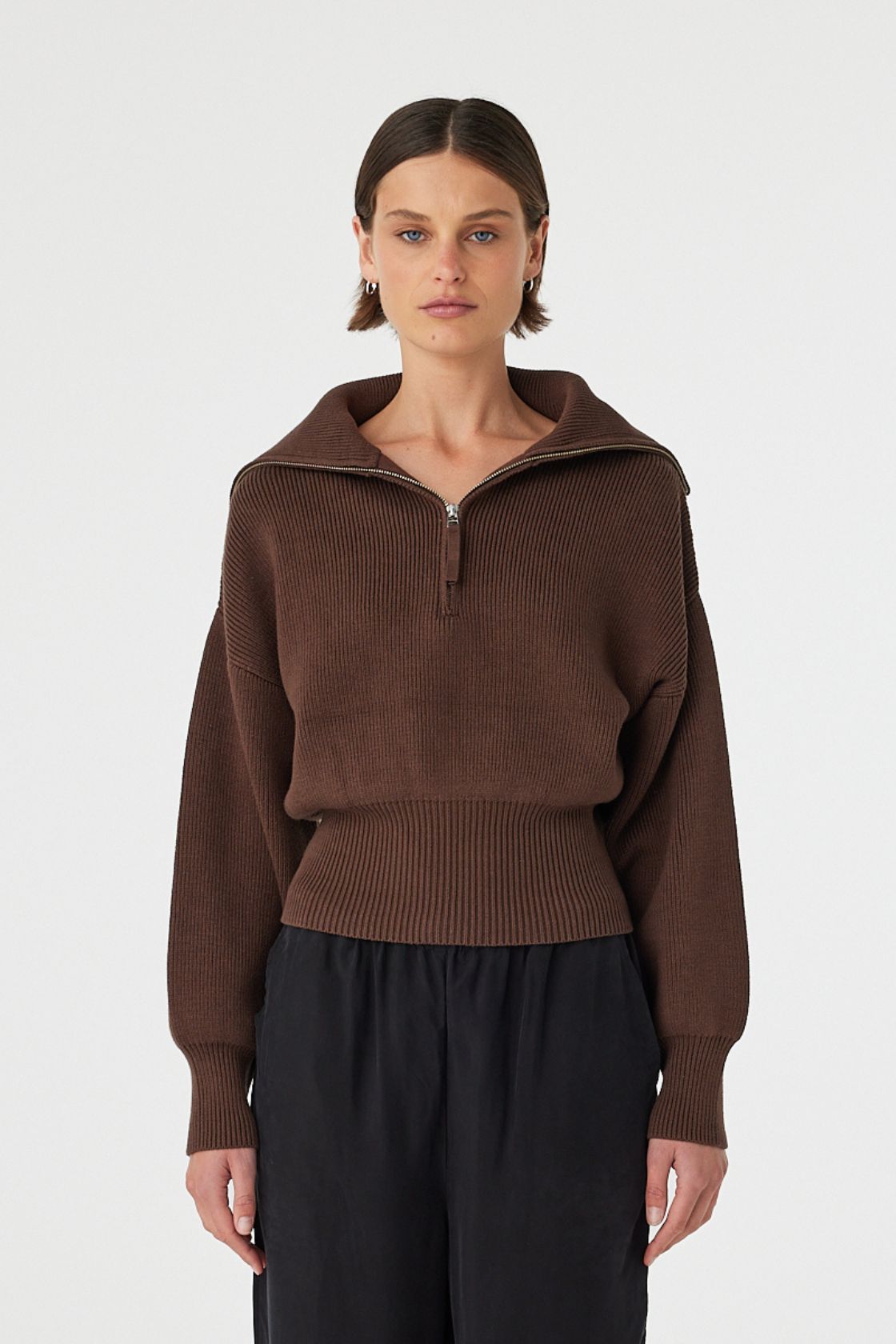 Marley zip sweater in espresso worn front on, showcasing the ribbed knit texture, exaggerated funnel neck collar and 1/4 zip detail, styled with black wide-leg pants 