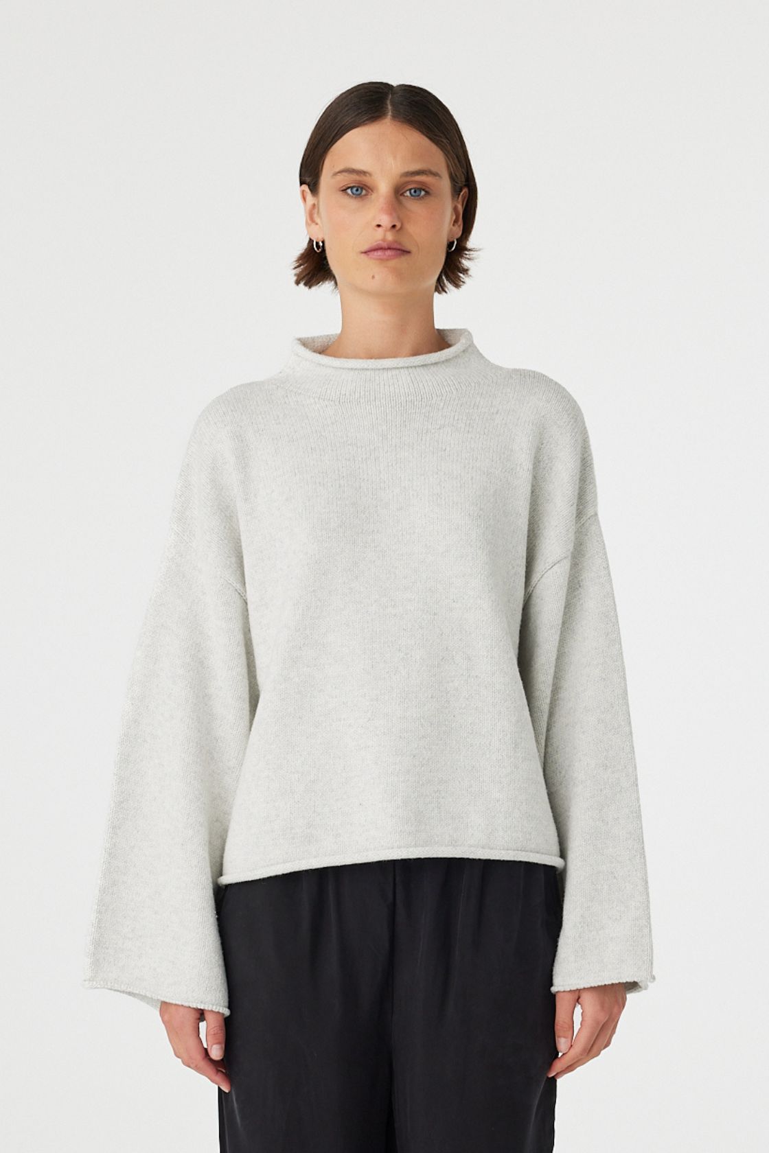 Maeve sweater in snow marle worn front on, featuring a relaxed fit, funnel neckline and cropped length, styled with black wide leg pants