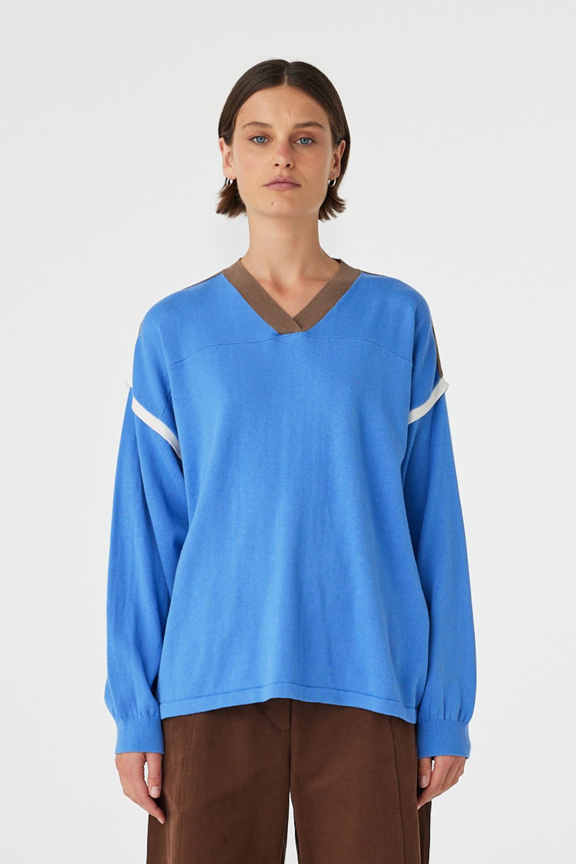 Close up of Eden long sleeve tee in royal blue and espresso worn front on, featuring an oversized slouchy fit, ribbed V-neckline and contrast shoulder detailing, styled with brown trousers