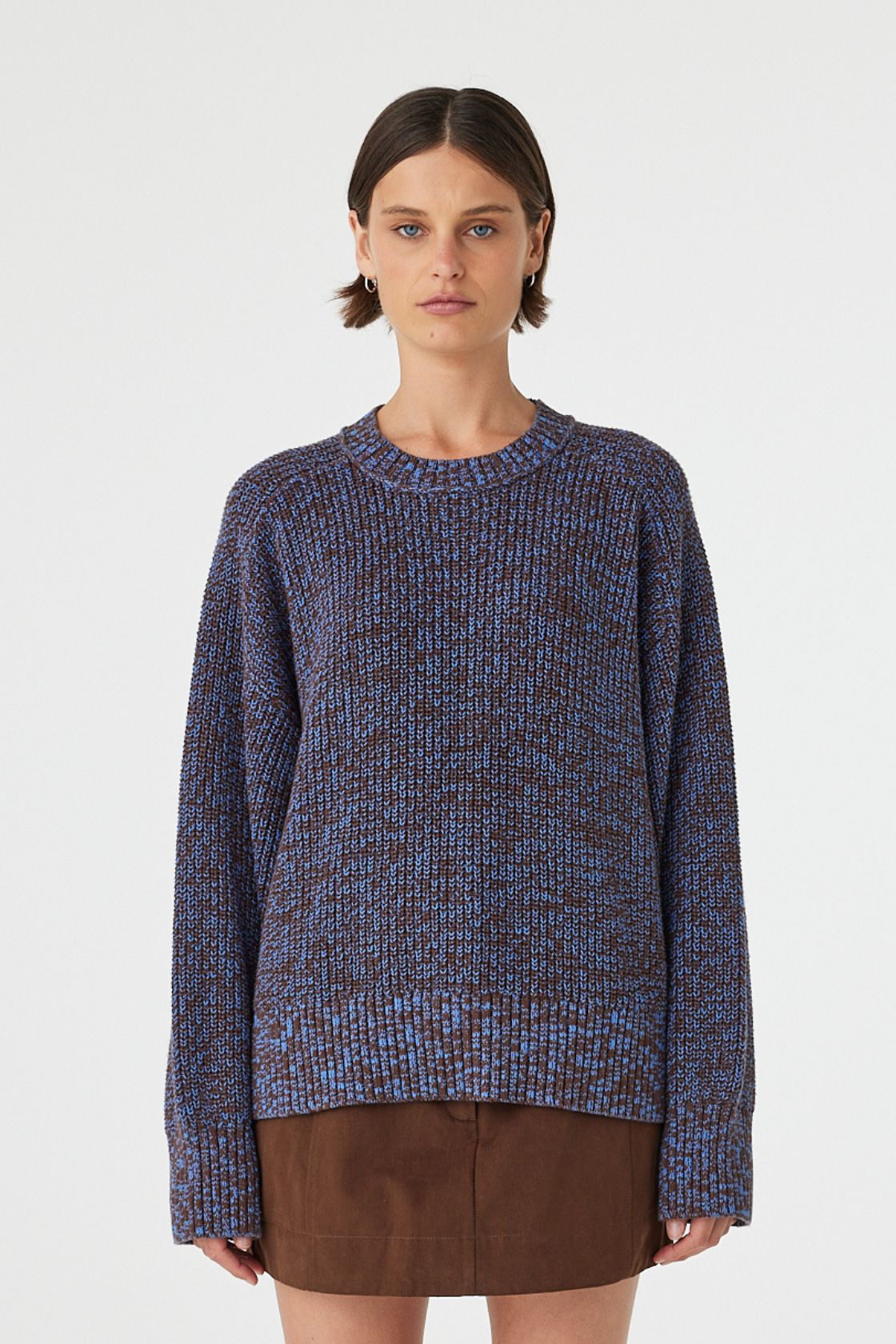Solene sweater in chocolate and royal blue mottled cotton knit worn front on, featuring an oversized fit, raglan sleeves and ribbed neckline, styled with a brown mini skirt