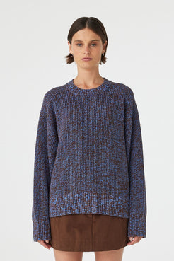 Solene sweater in chocolate and royal blue mottled cotton knit worn front on, featuring an oversized fit, raglan sleeves and ribbed neckline, styled with a brown mini skirt
