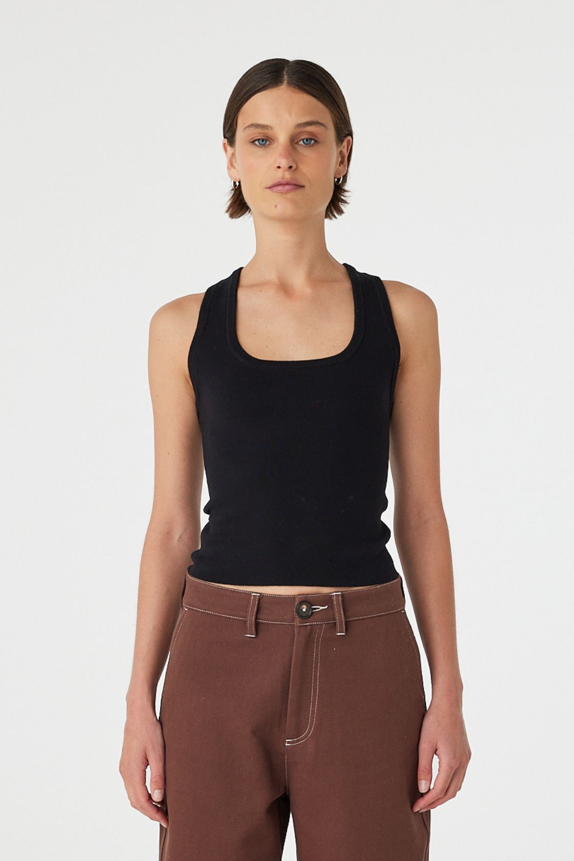 Full body front view of Sable Top black, racerback knit tank styled with brown pants.