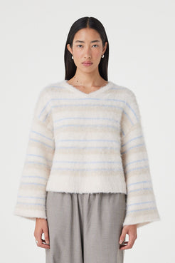 Front view of the Lucca Sweater in taupe and blue stripe featuring a soft fluffy knit texture, relaxed cropped silhouette and deep V-neckline styled with relaxed taupe pants