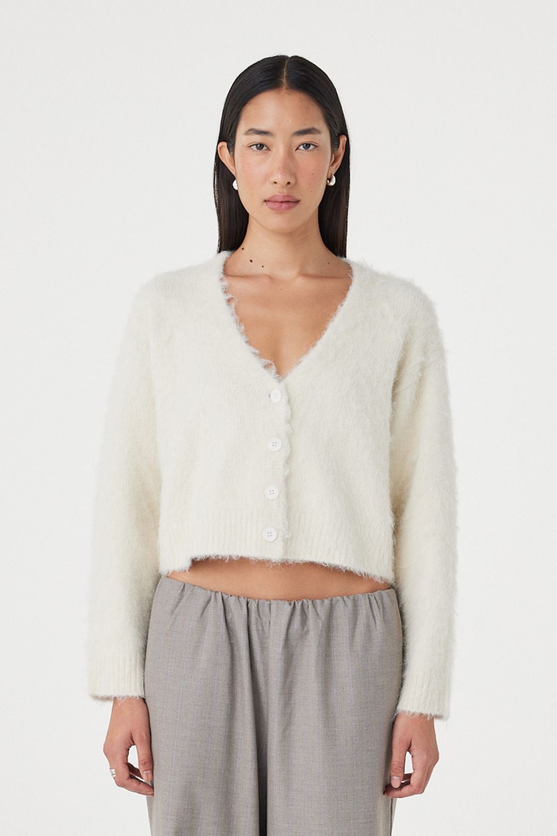 Full-length front view of the Liora Fluffy Cardigan in cream styled with relaxed taupe pants, featuring a button-up front, deep neckline and easy oversized drape