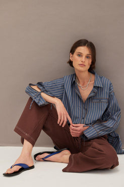 Blue pinstripe oversized shirt paired with chocolate wide leg pants and minimal sandals, relaxed tailored look