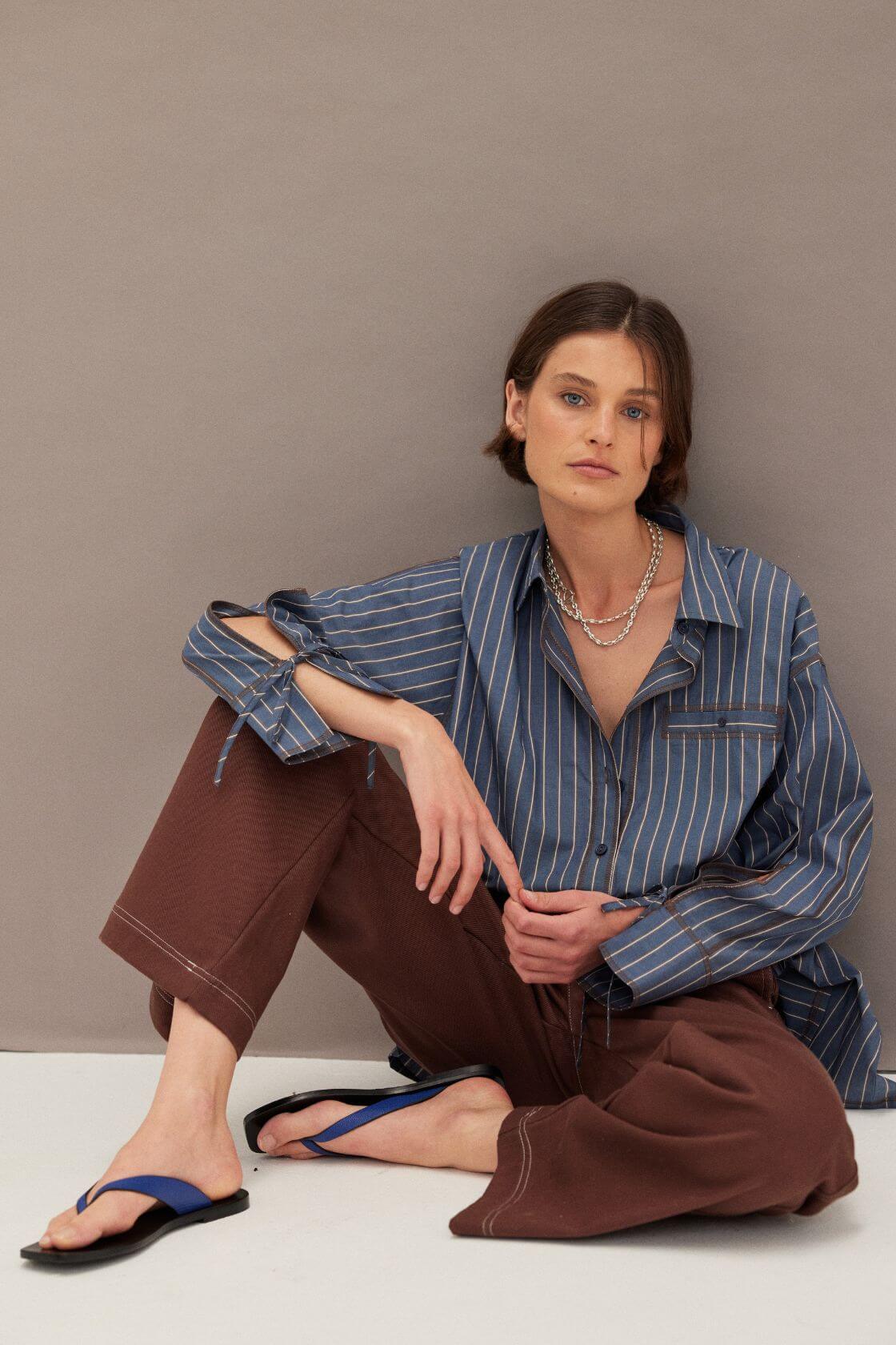 Blue pinstripe oversized shirt paired with chocolate wide leg pants and minimal sandals, relaxed tailored look