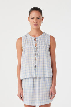 Model wears powder blue check blouse with front tie closures and ruched yoke. Relaxed cotton fit with airy texture.