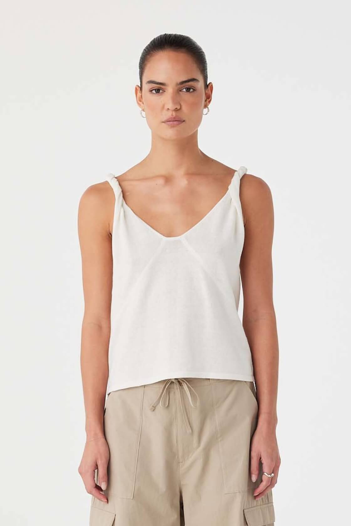 Model wearing cream linen–organic cotton tank with twist straps and V-neckline, styled with relaxed taupe cargo pants.