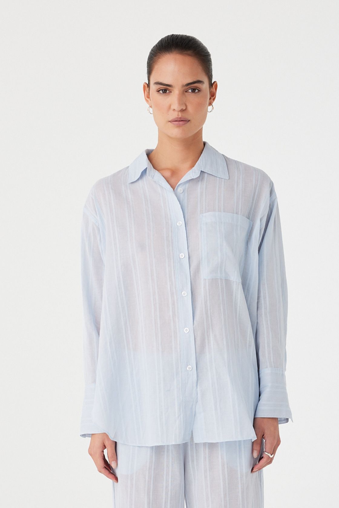 Model in oversized textured cotton shirt with subtle sheer finish and relaxed drape.