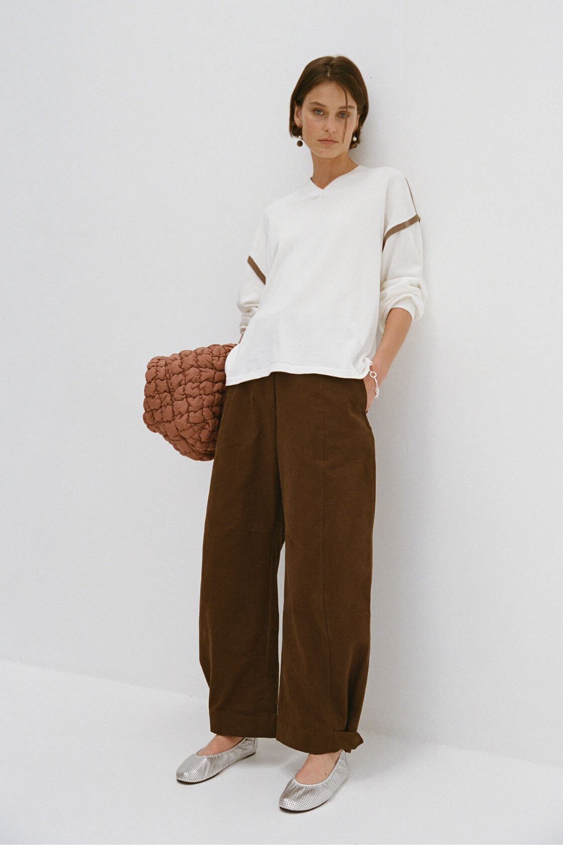 Cream oversized knit paired with wide leg brown pants and textured clutch, neutral capsule outfit styling