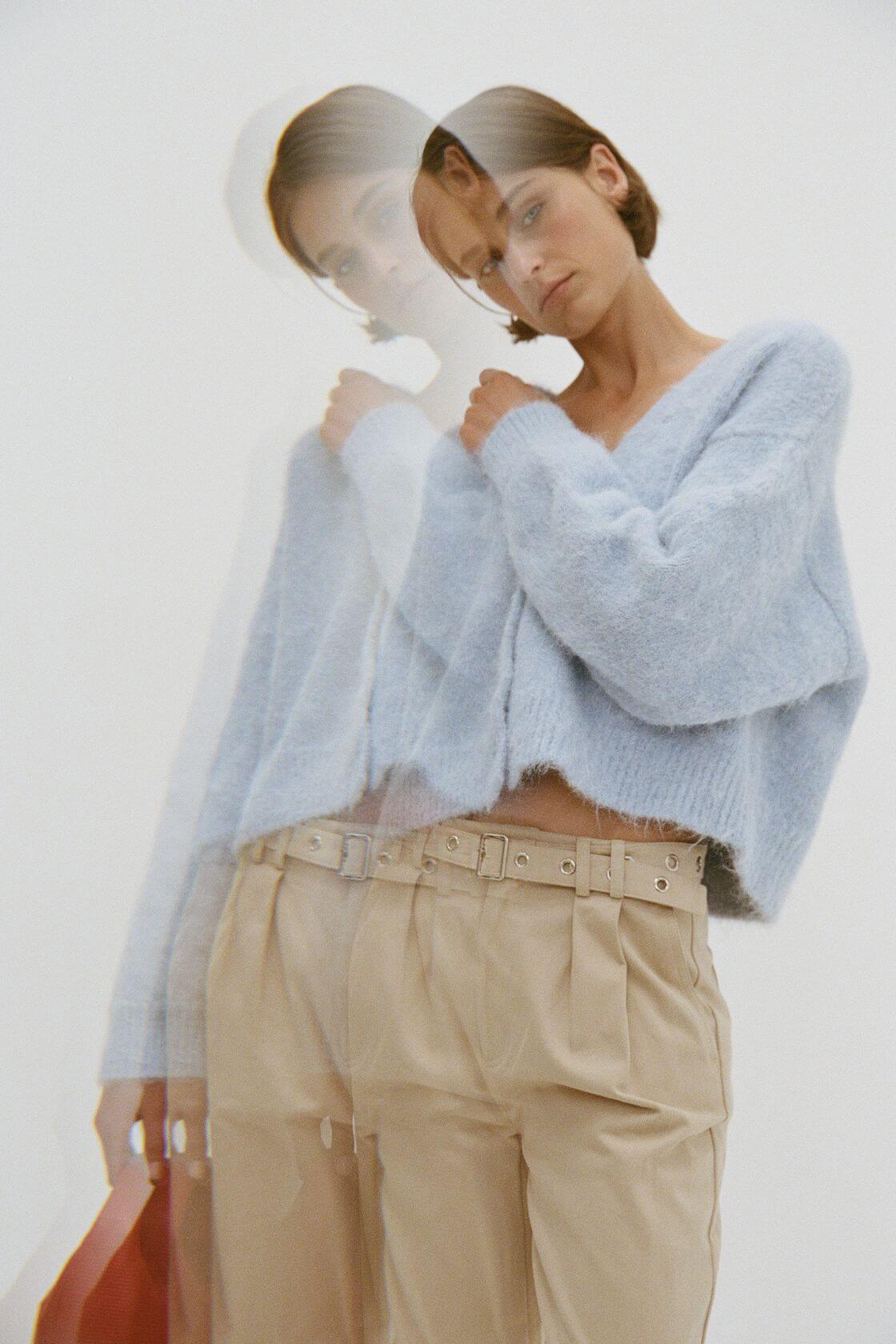 Soft blue cropped knit sweater with beige tailored trousers, relaxed fit with textured finish