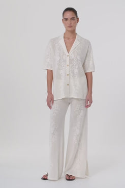 Model moves in full-length crochet pants made from a hemp cotton blend, showing fluid drape and breathable texture. Styled for warm-weather layering with matching shirt.